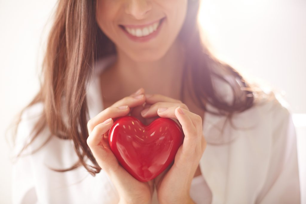 Close-up of smiling female holding red heart